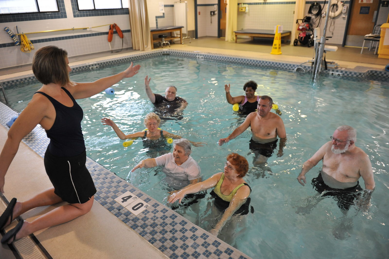 Paciente ejercitándose dentro de una piscina de rehabilitación acompañado por su terapeuta