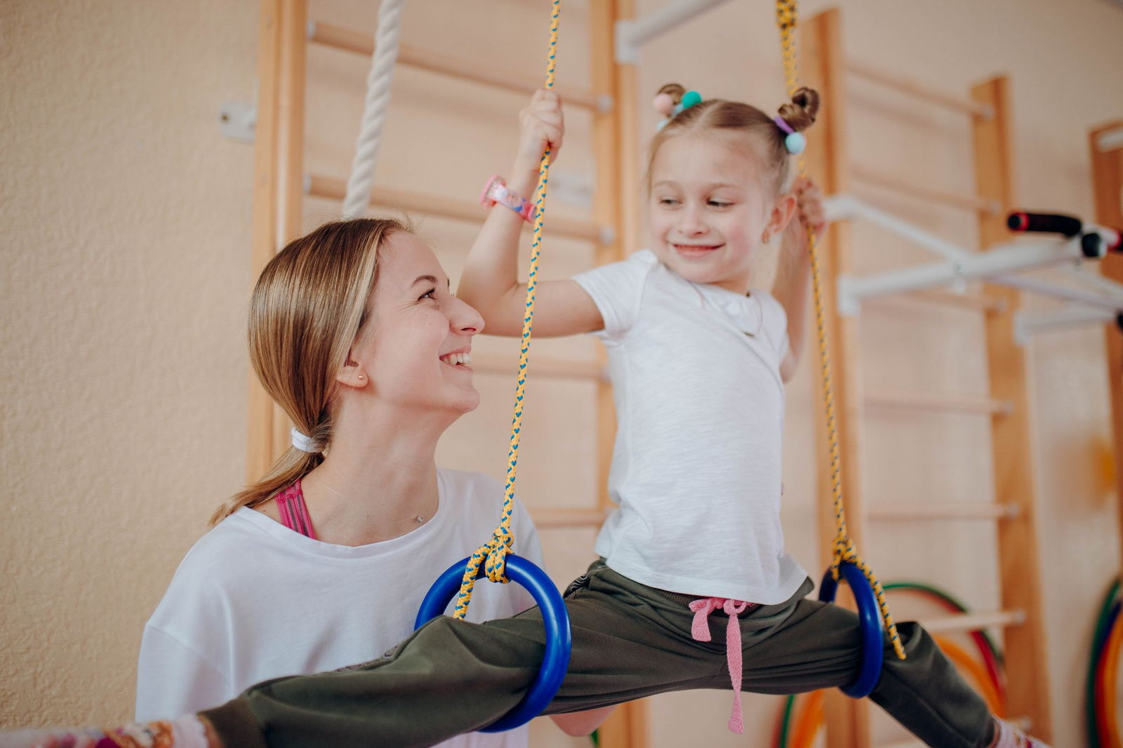 Fisioterapeuta pediátrica ayudando a un niño a caminar entre barras paralelas